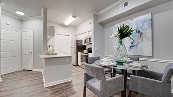 A dining room with a table set for two and a kitchen area in the background.